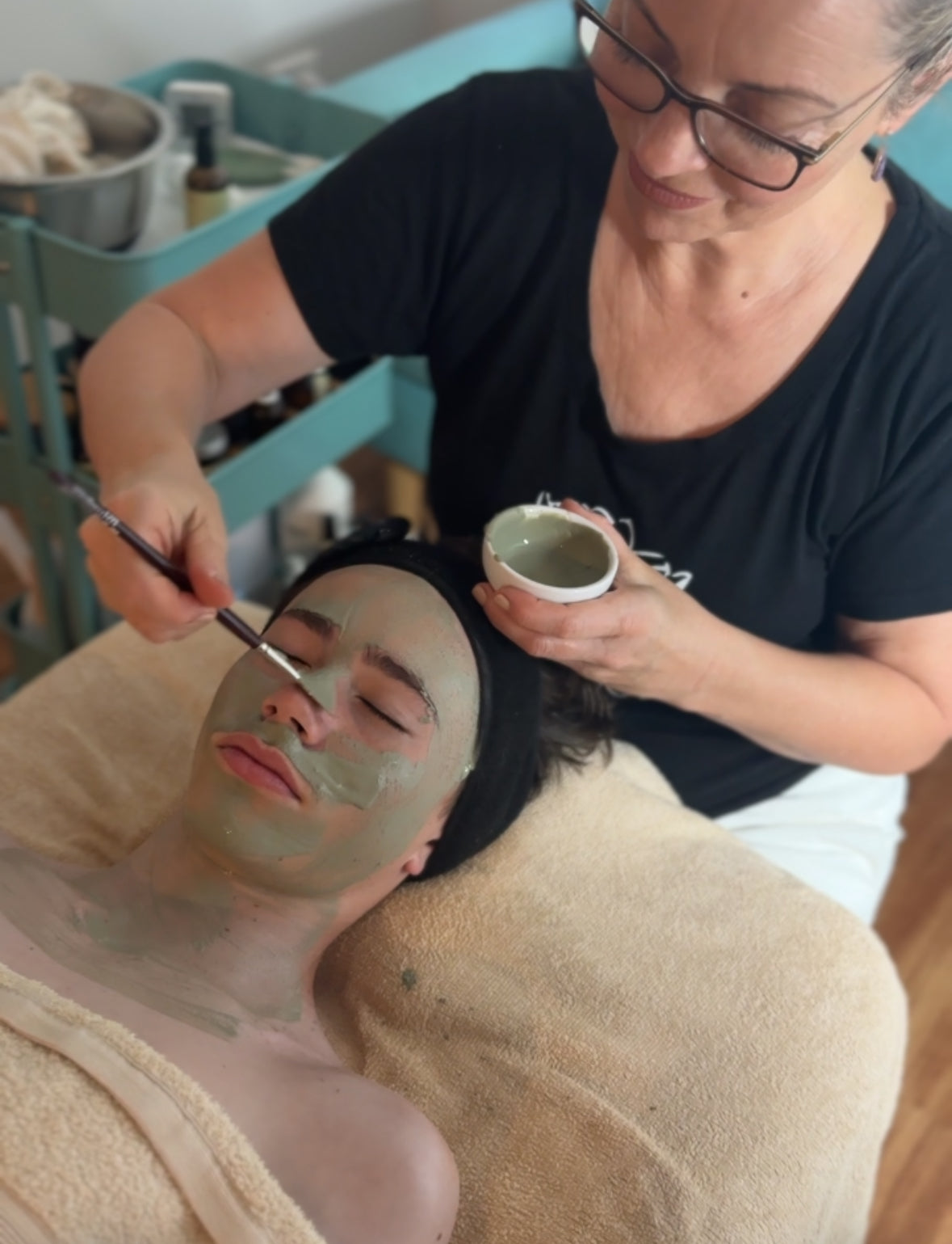 Person receiving a facial treatment with a French clay face mask applied to their face.